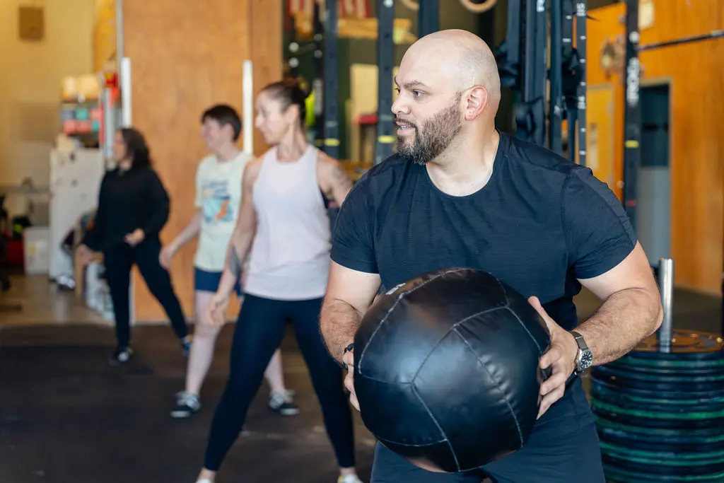 Member holding a medicine ball during a group strength and conditioning class at Polaris in Ballard