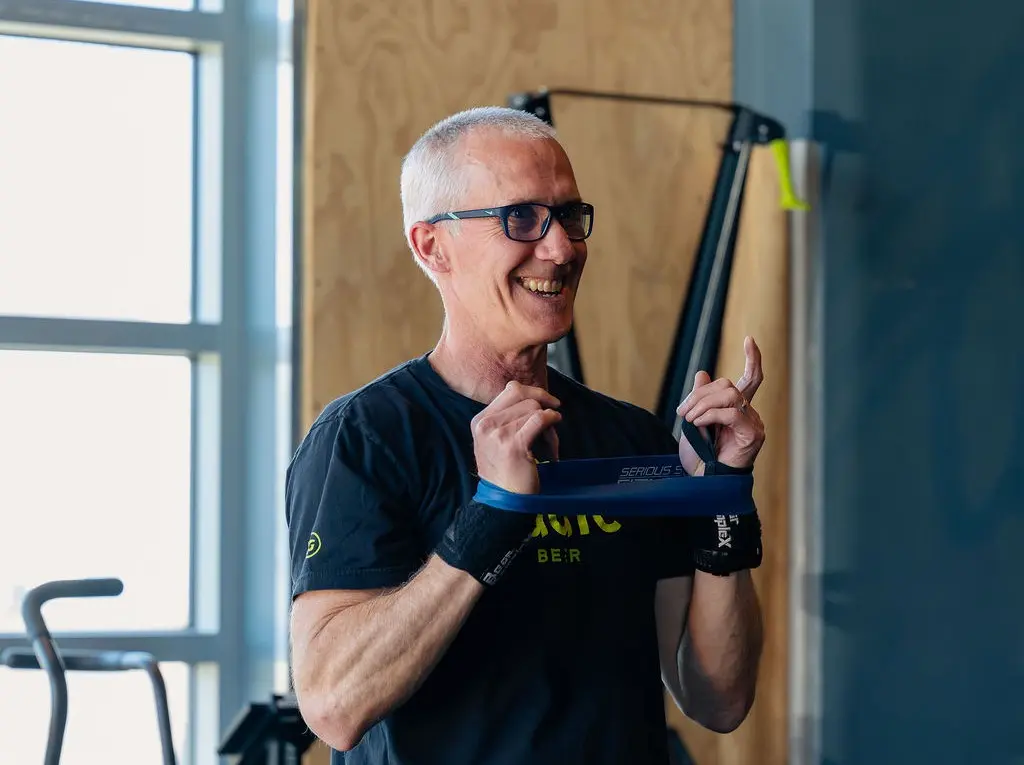 Smiling member working with a resistance band on his individualized design program